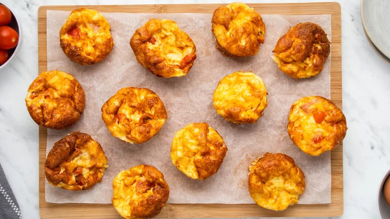 Miniature quiche bites on paper-lined cutting board.