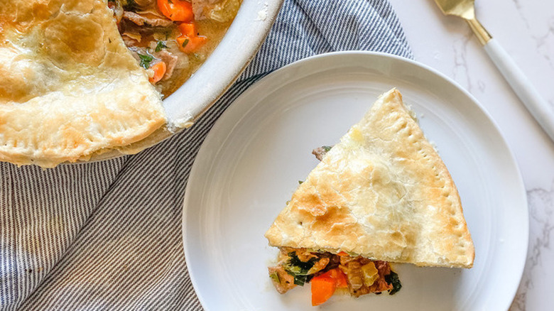 Slice of beef pie with meat-veggie filling and browned crust.