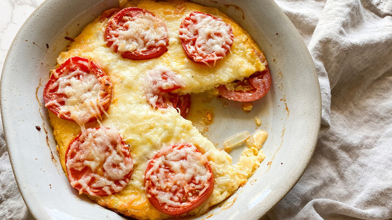 Cheese and tomato pie baked in white casserole dish. 