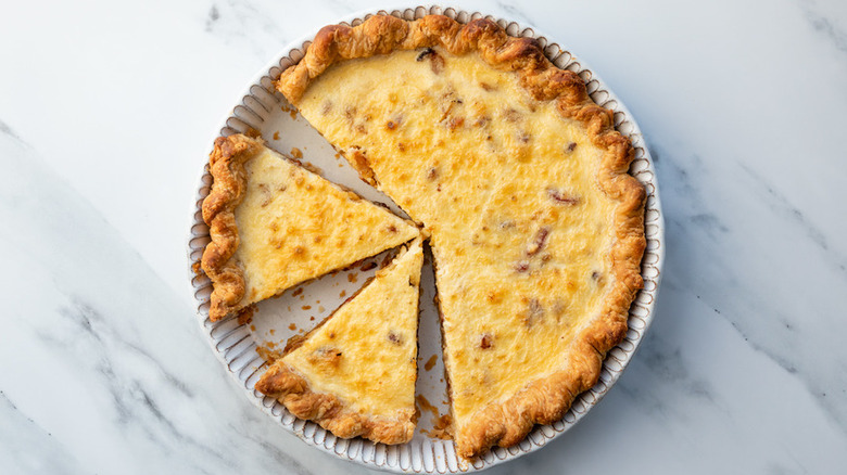 Baked round quiche with two slices cut away.