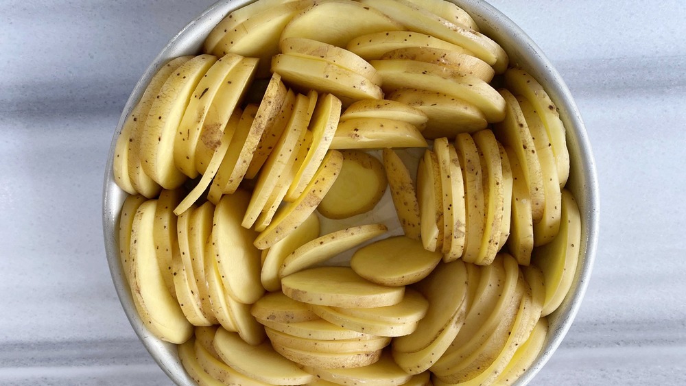 scalloped potatoes being placed in pan