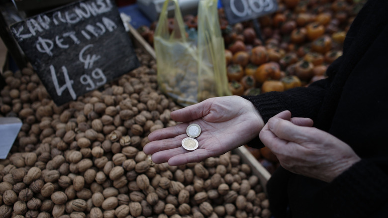 Hand holding euros above bin of nuts