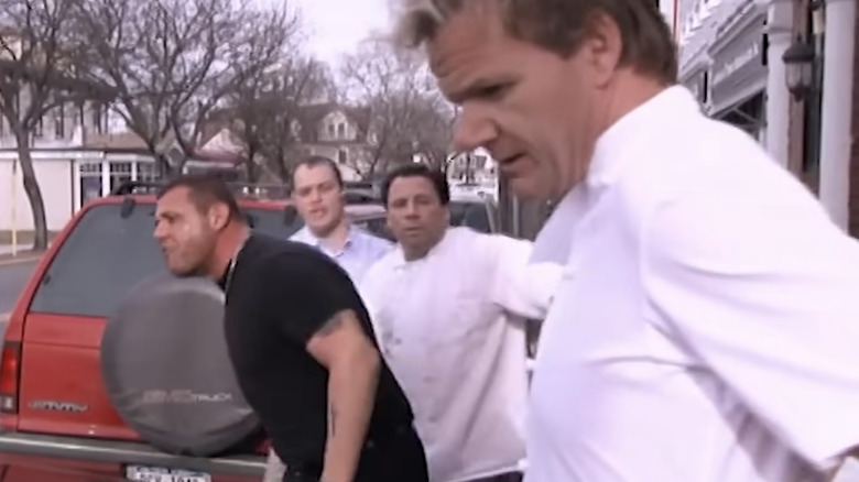 Gordon stands near red SUV wearing chef whites