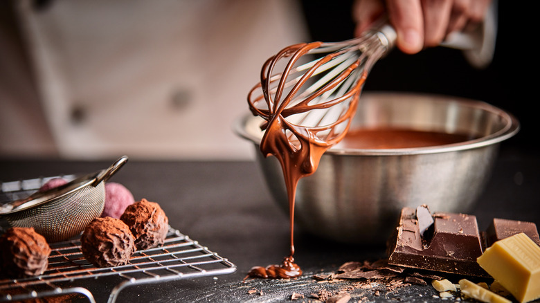 chocolate truffles, chocolatier prepping chocolate in metal mixing bowl with whisk