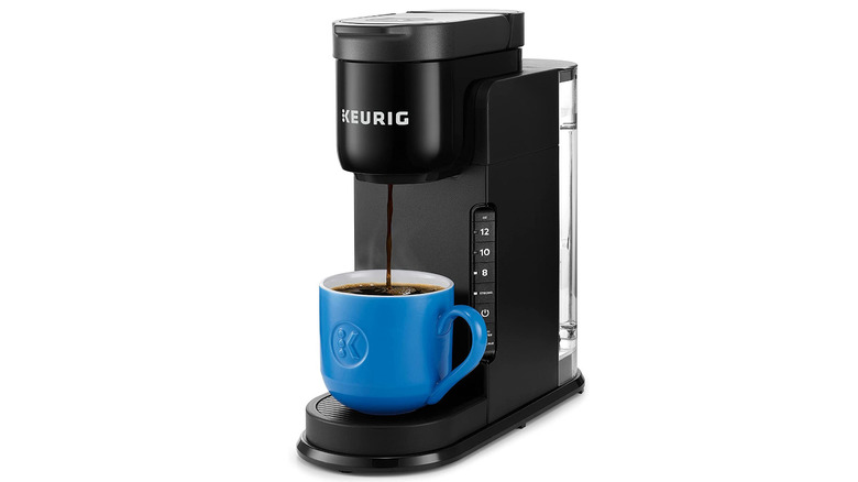 Black single serve coffee pod brewer with blue mug.