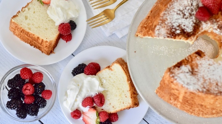 angel food cake covered with powdered sugar and fresh fruit with two slices on plates