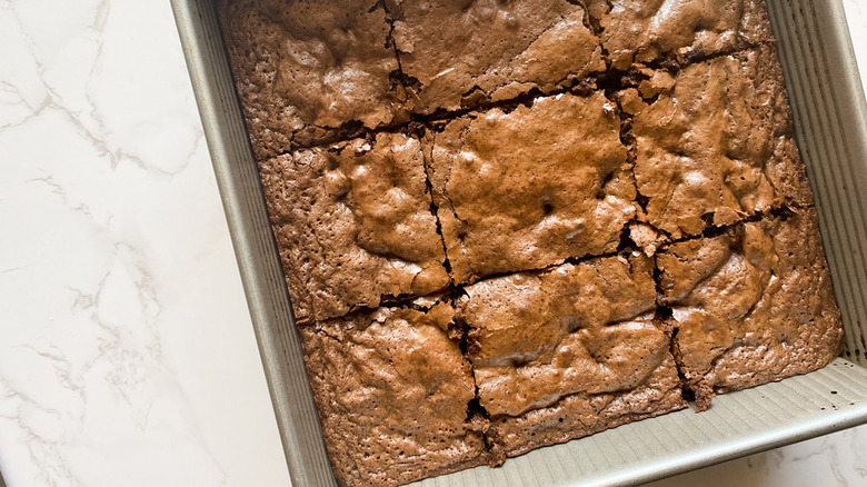 metal pan of cut brownies on a white marble counter