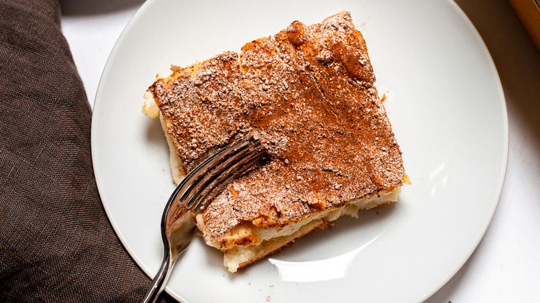 crescent roll cheesecake dusted with powdered sugar and cinnamon on a white plate