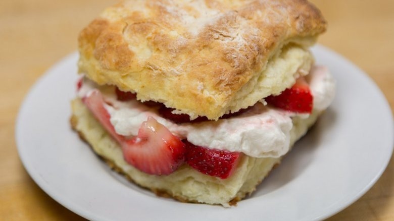 light and flaky strawberry shortcake filed with fresh strawberries and whipped cream on a white plate