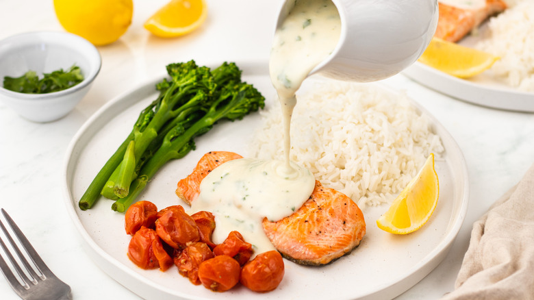 pouring creamy sauce over trout