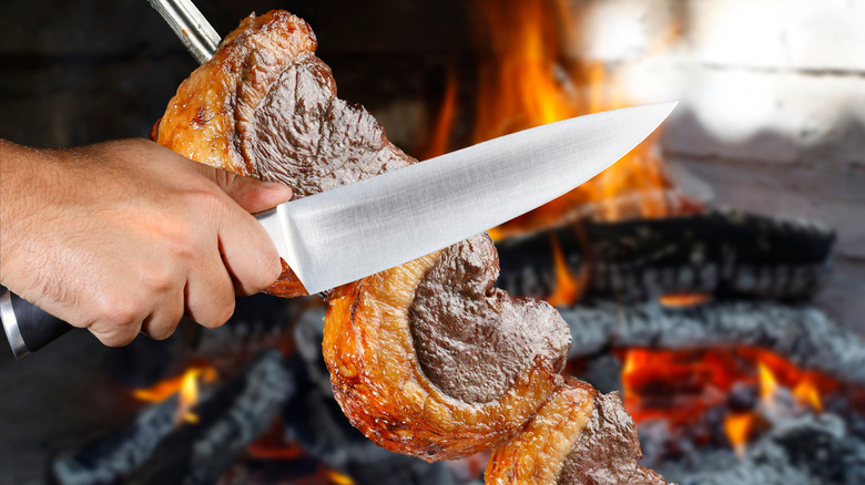 Steak being sliced off skewer