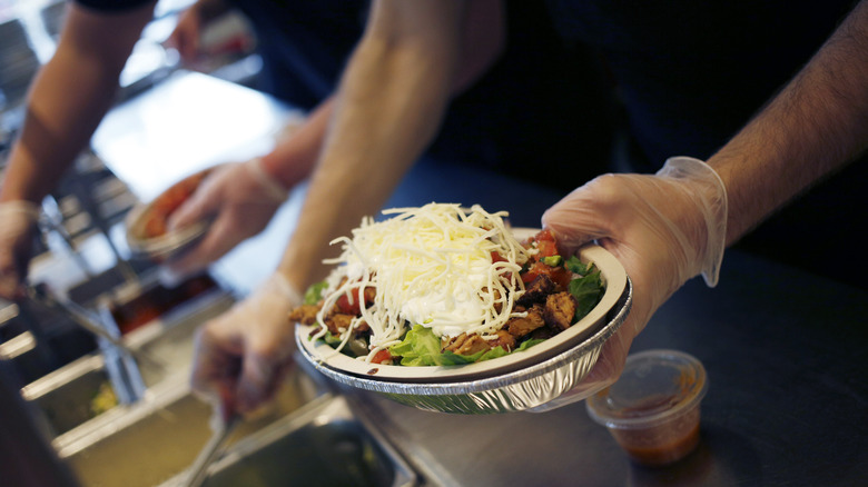 employee preparing chipotle bowl