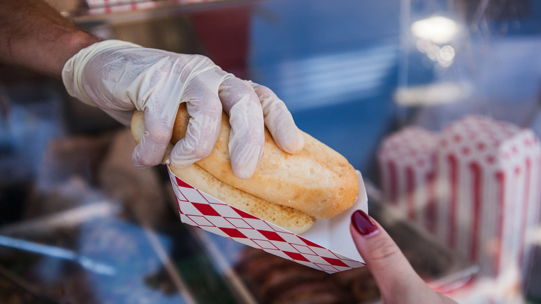 Hot dog vendor handing hot dog to woman