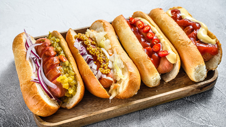 Hot dogs topped with vegetables and condiments 