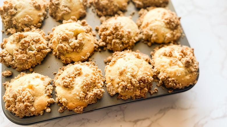 muffin tin with cinnamon muffins topped with strudel