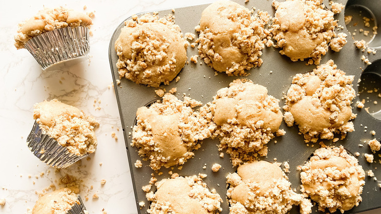 coffee cake muffins in a tin and on the counter in shiny silver muffin wrappers