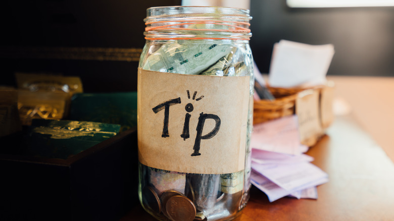 glass tip jar with cash in it