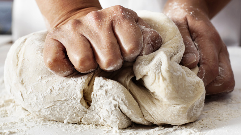 baker kneading pizza dough