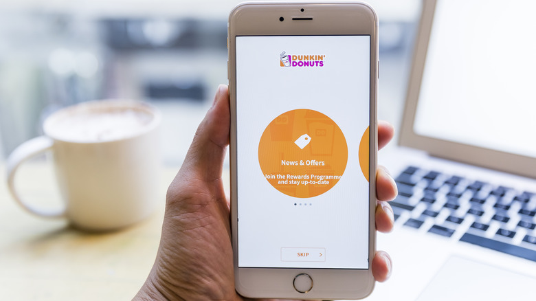 Hand holding iPhone using Dunkin' app