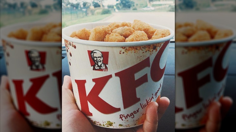 Hand holding bucket of popcorn chicken