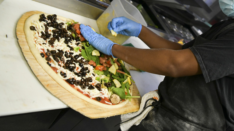 Toppings being put on pizza 