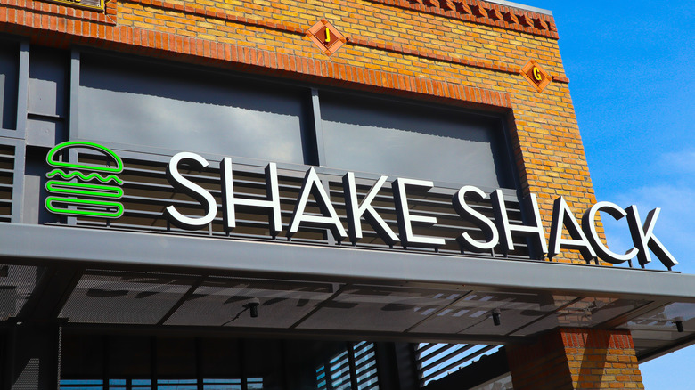 Shake Shack sign with green burger logo and white lettering