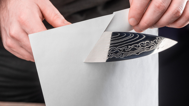 man cutting through paper with a knife