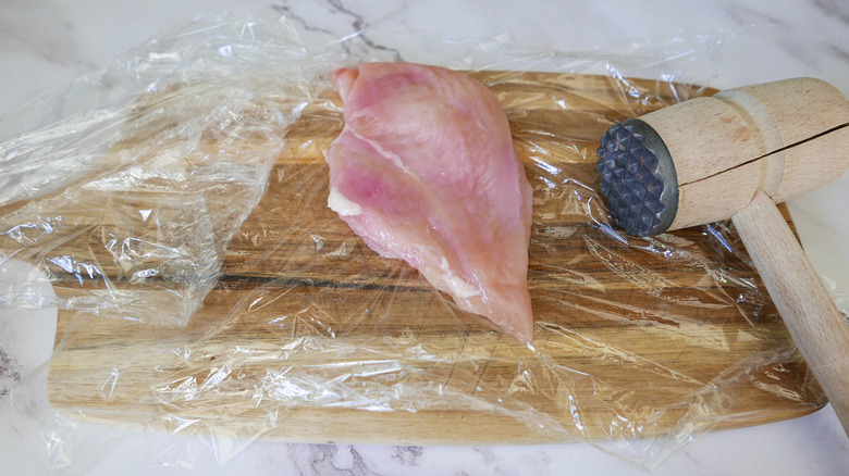 raw chicken with meat mallet