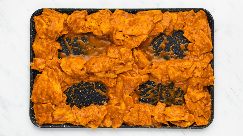 sauce-covered tortilla chips on baking sheet