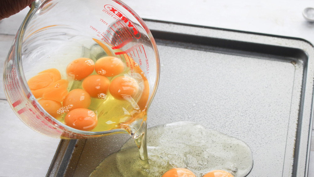 eggs pouring onto sheet pan for sheet pan fried eggs