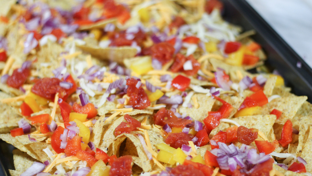 sheet pan nachos on pan with cheese and veggies