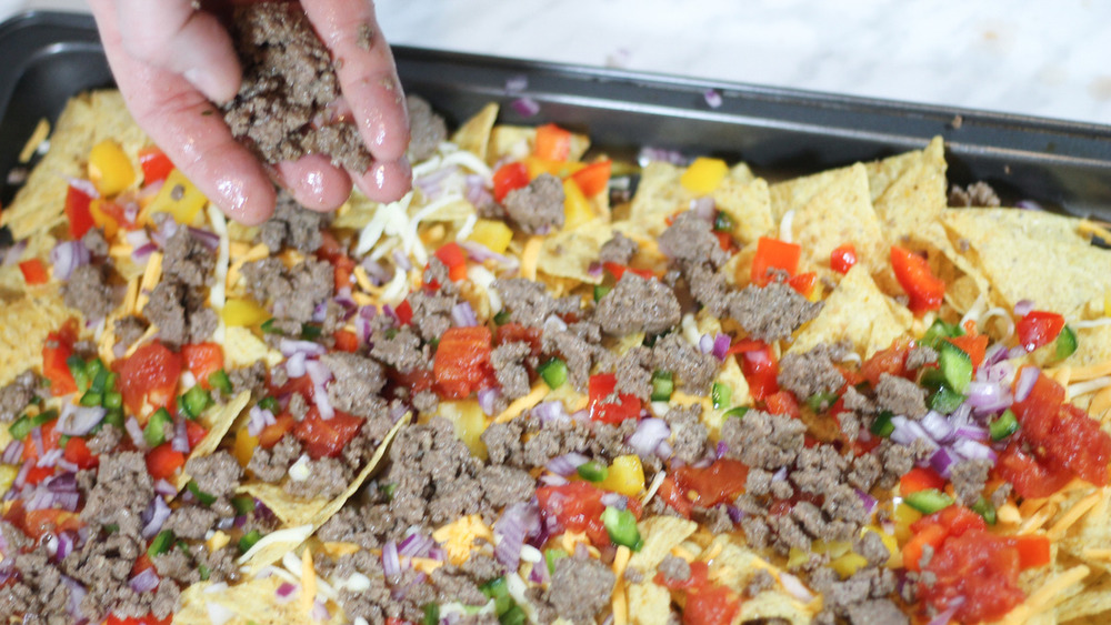 adding beef to sheet pan nachos