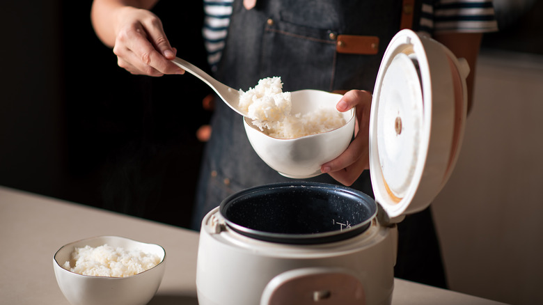 person removing rice from rice cooker