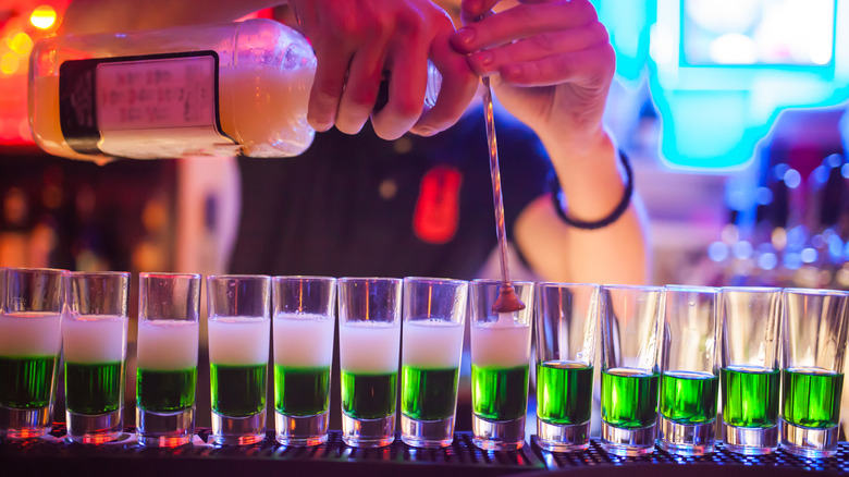 Bartender pouring drinks into shot glasses