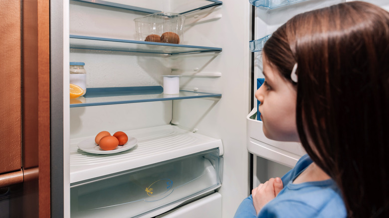 worried girl looking into an empty refrigerator