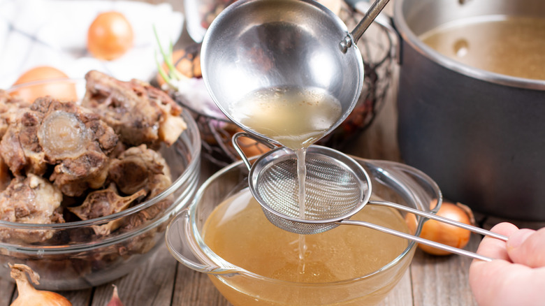 Pouring bone broth through strainer