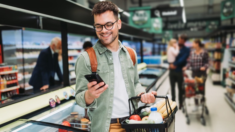 man using cell phone in grocery store