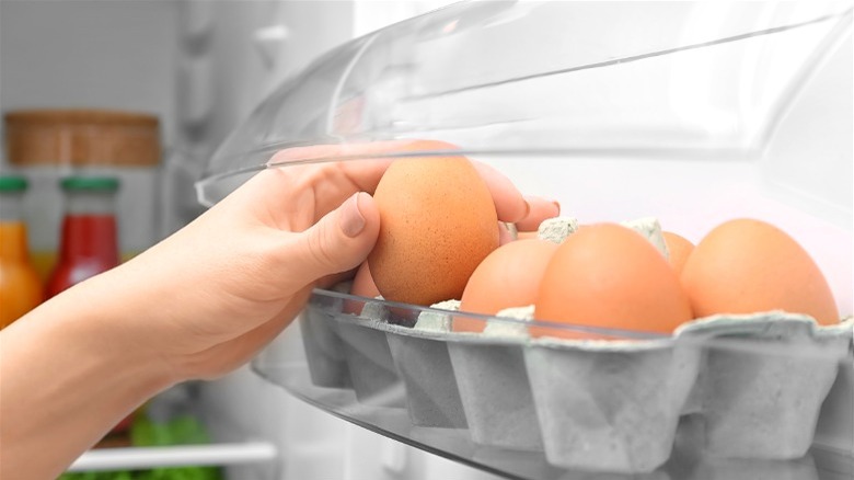 Hand grabbing egg from refrigerator 