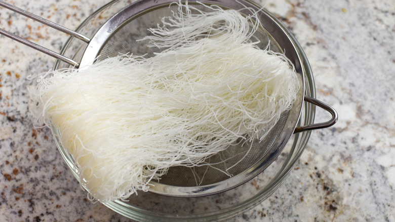 uncooked rice noodles in colander