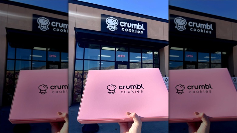 Hand holding pink Crumbl Cookies box