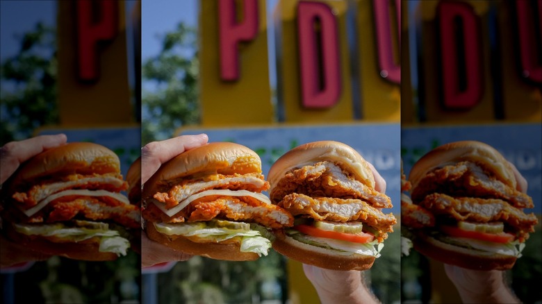 Hands holding two chicken burgers