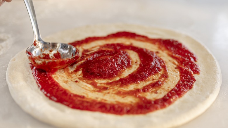 sauce being spread on dough