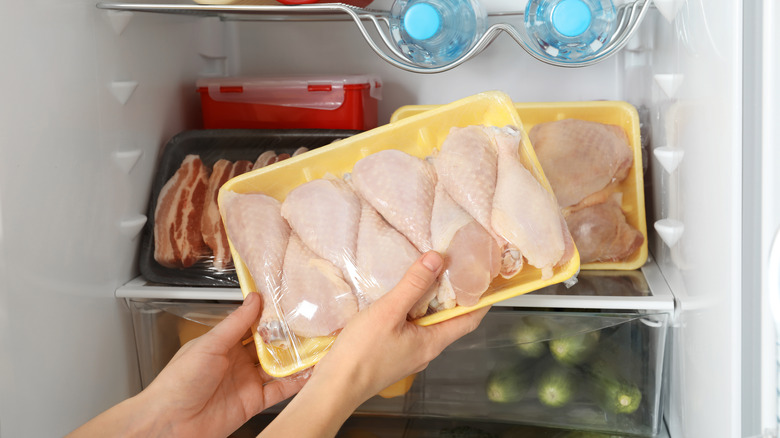 person pulling package of chicken drumsticks out of the fridge