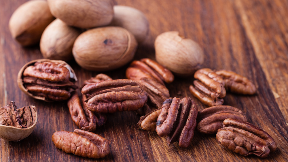 Pecans shelled and unshelled on wooden table