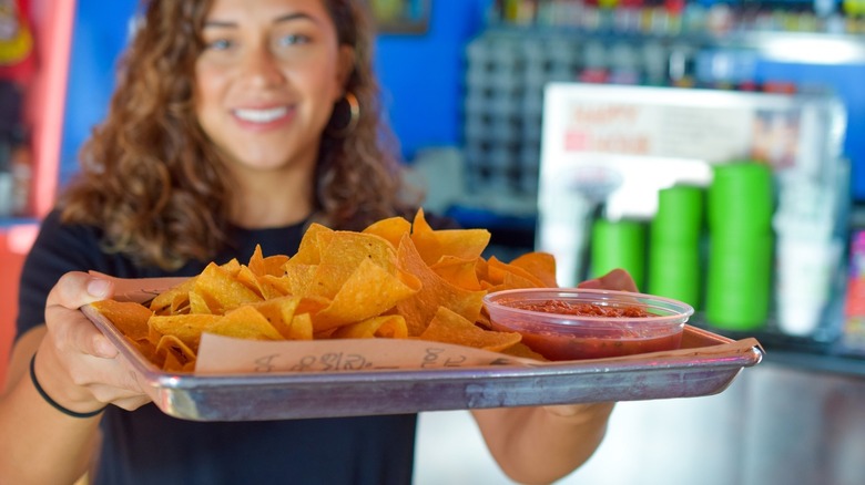 employee holding chips and salsa