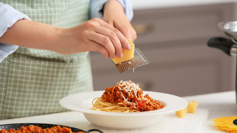 grating parmesan over spaghetti