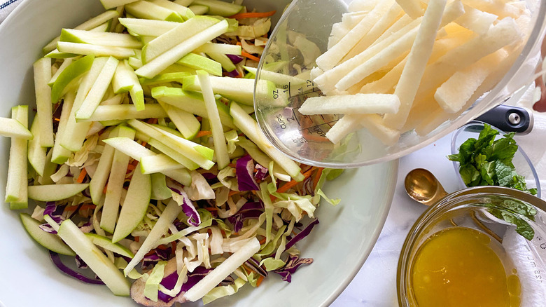 adding salad ingredients to bowl