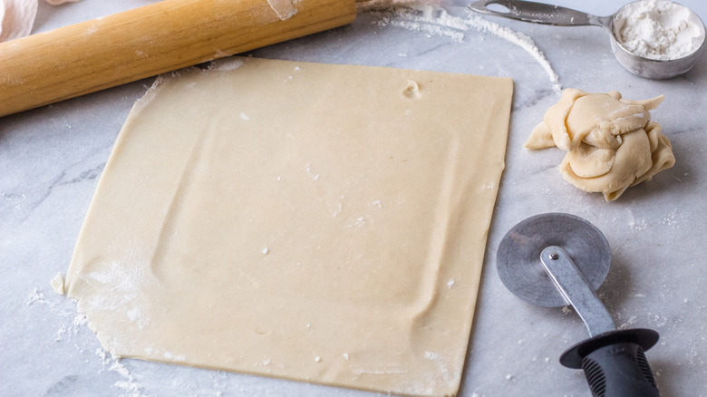 template for pie strips on pre-bought pie dough with pizza cutter and rolling pin