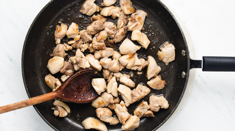 Diced chicken frying in pan