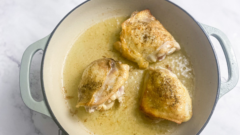 chicken cooking in a pan with oil